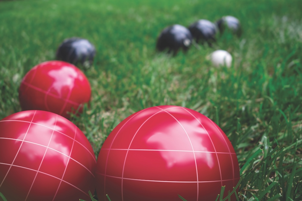 Italian Bocce Ball, Bocci Or Boccie Red And Blue White Balls On Green Lawn Close Up. An Ancient Games Played In The Roman Empire