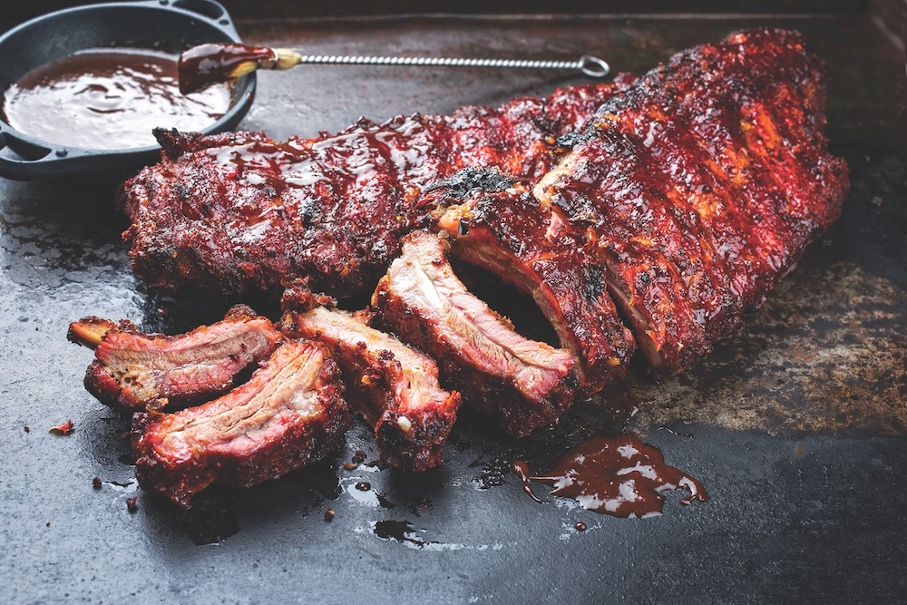 Barbecue Pork Spare Loin Ribs St Louis Cut With Hot Honey Chili Marinade Burnt As Closeup On An Old Rustic Board